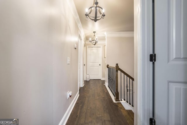 corridor featuring a chandelier, dark wood finished floors, ornamental molding, and baseboards