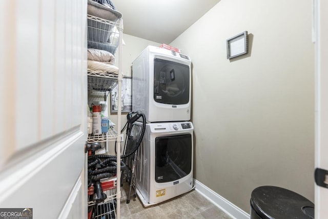 laundry room featuring laundry area, baseboards, and stacked washer / dryer