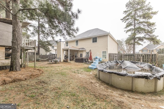 back of house with a fenced backyard and a fenced in pool