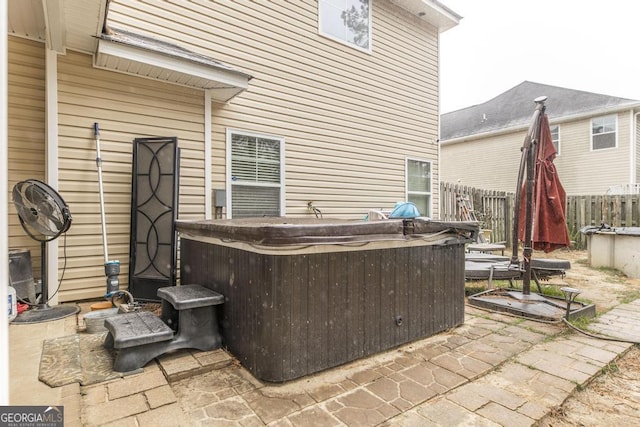 view of patio featuring a hot tub and fence