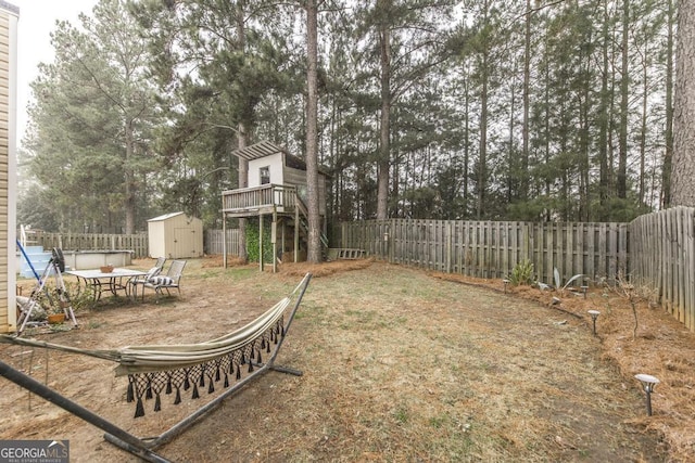 view of yard with a shed, a fenced backyard, and an outbuilding