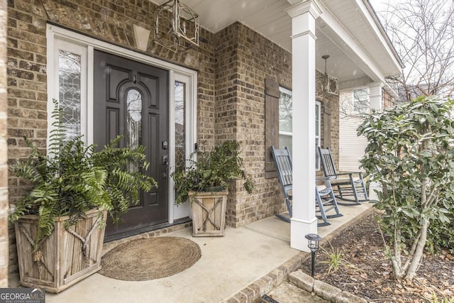 property entrance featuring a porch and brick siding