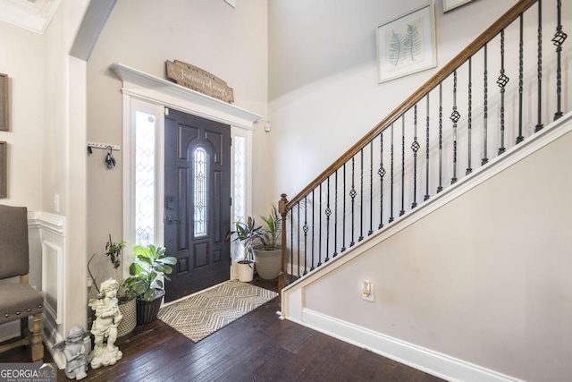 entrance foyer with arched walkways, a high ceiling, hardwood / wood-style floors, and stairs