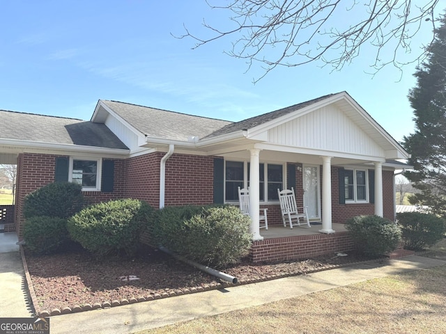 view of front of house featuring brick siding, roof with shingles, and a porch