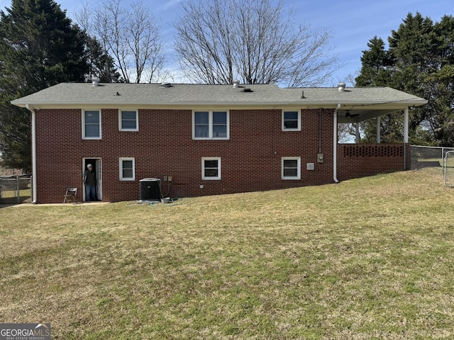 rear view of house featuring a yard, brick siding, central AC, and fence