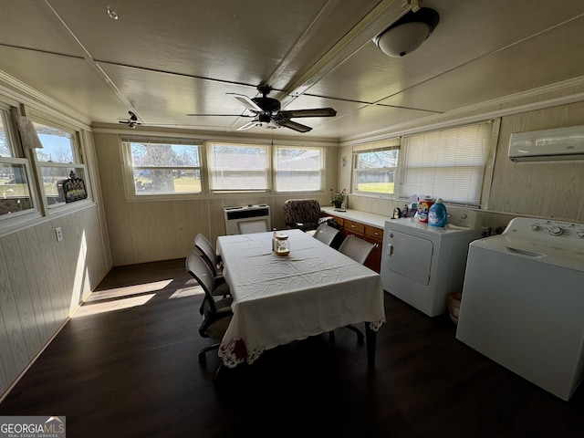 dining area with dark wood-style floors, wooden walls, a wealth of natural light, and washing machine and clothes dryer