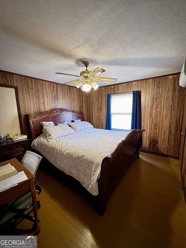 bedroom with hardwood / wood-style flooring, wooden walls, a ceiling fan, and a textured ceiling