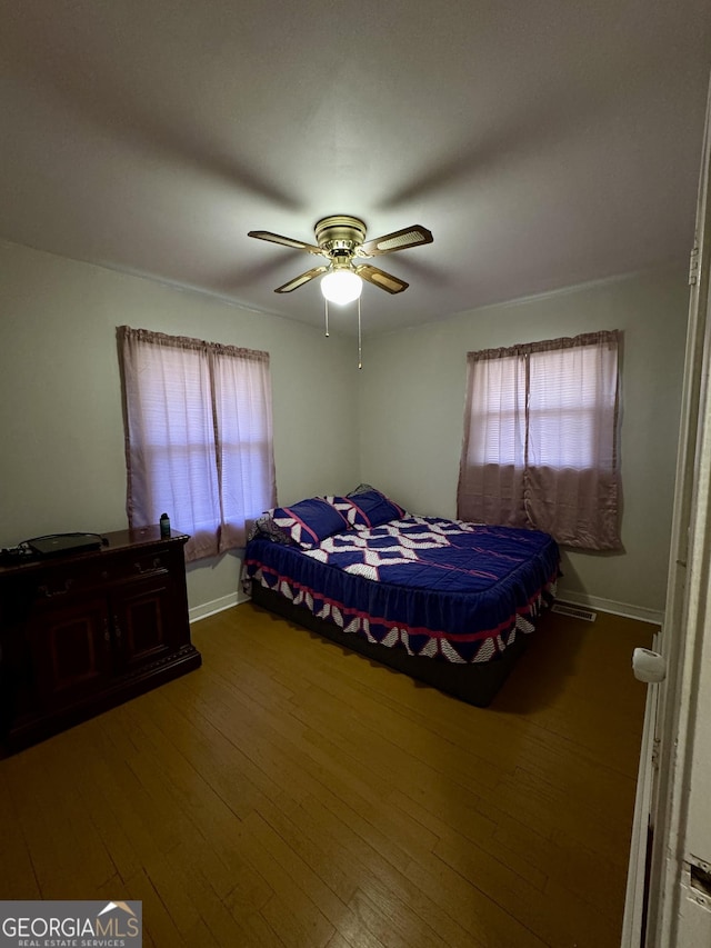 bedroom featuring wood-type flooring, visible vents, baseboards, and ceiling fan