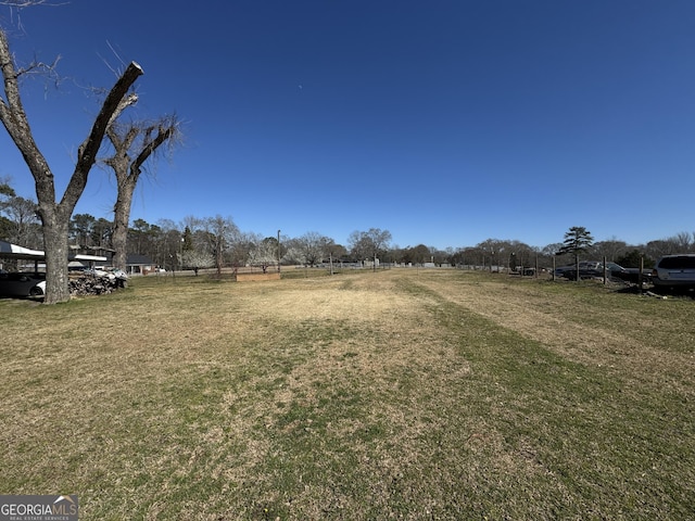 view of yard with fence and a rural view