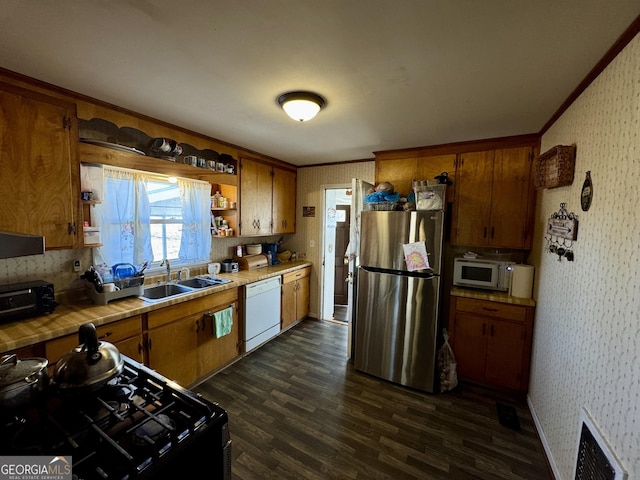 kitchen with dark wood-style floors, visible vents, a sink, white appliances, and wallpapered walls