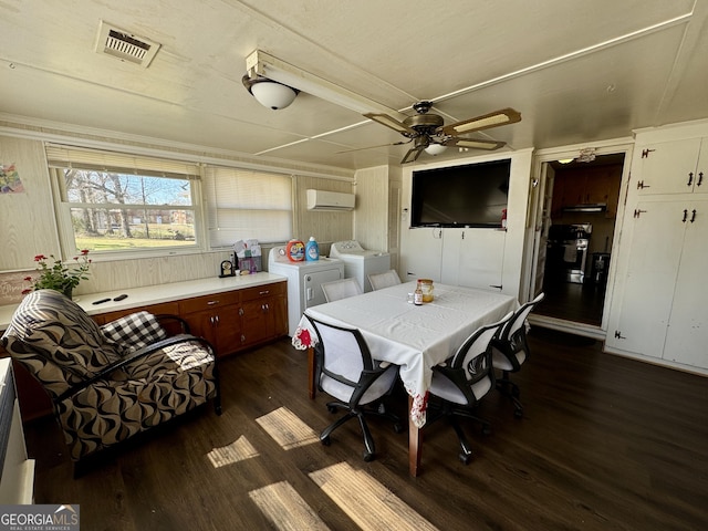 dining space with ceiling fan, dark wood-type flooring, visible vents, a wall mounted AC, and independent washer and dryer