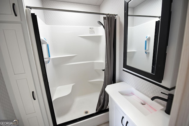 full bath featuring a shower stall, vanity, and wallpapered walls