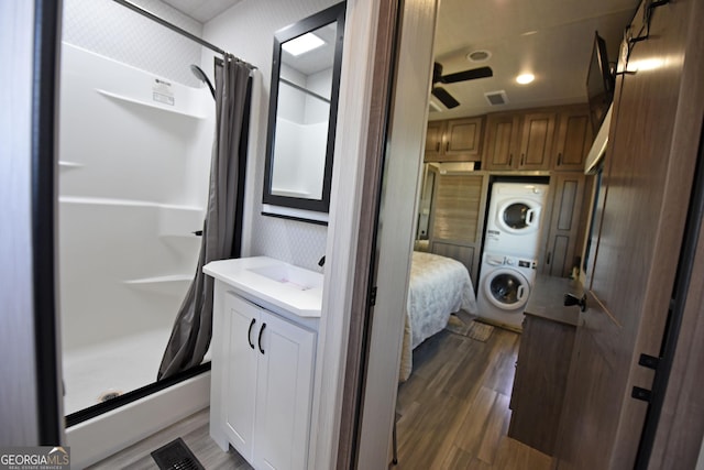 full bathroom featuring stacked washer and dryer, visible vents, a shower stall, vanity, and wood finished floors