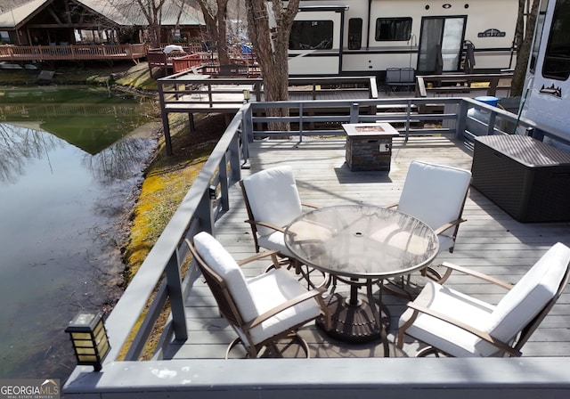 view of patio with outdoor dining area and a deck with water view