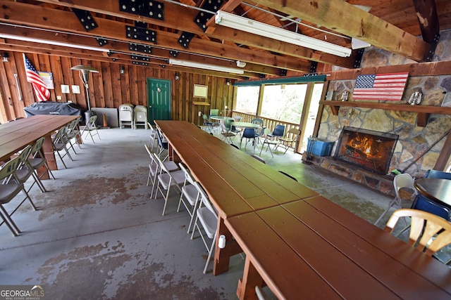 unfurnished dining area featuring concrete flooring, a fireplace, and wooden walls