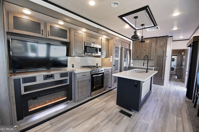 kitchen featuring appliances with stainless steel finishes, light countertops, a sink, and tasteful backsplash