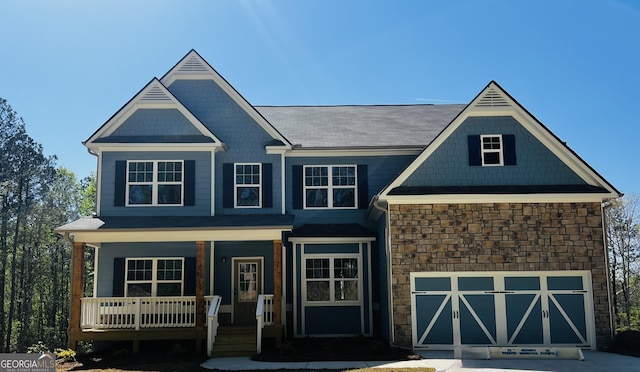 view of front of house with a porch, stone siding, a garage, and concrete driveway