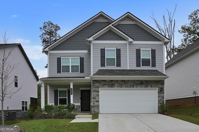 craftsman-style house with a garage, concrete driveway, stone siding, covered porch, and a front lawn