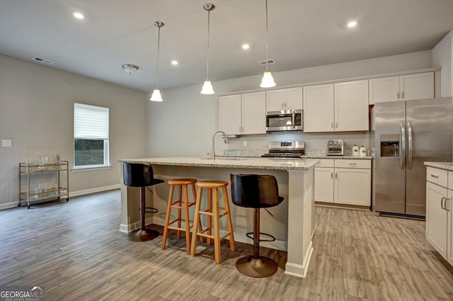 kitchen featuring visible vents, light wood-style flooring, appliances with stainless steel finishes, white cabinetry, and a sink