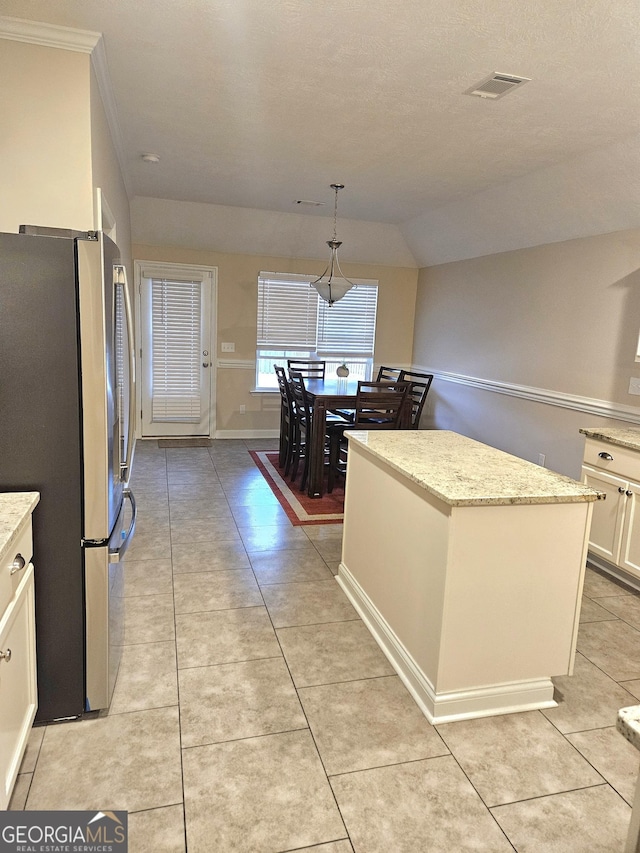 kitchen with visible vents, light stone counters, light tile patterned flooring, and freestanding refrigerator