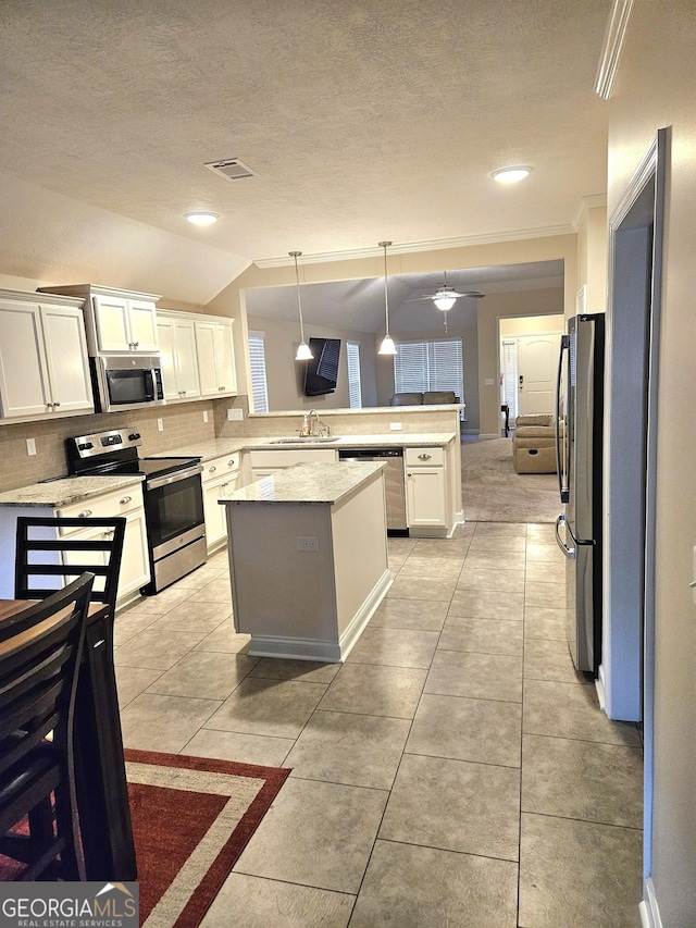 kitchen featuring decorative backsplash, appliances with stainless steel finishes, a peninsula, white cabinetry, and a sink