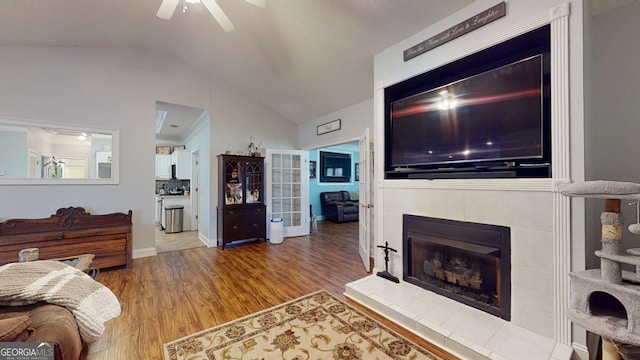 living room featuring a fireplace, a ceiling fan, vaulted ceiling, and wood finished floors