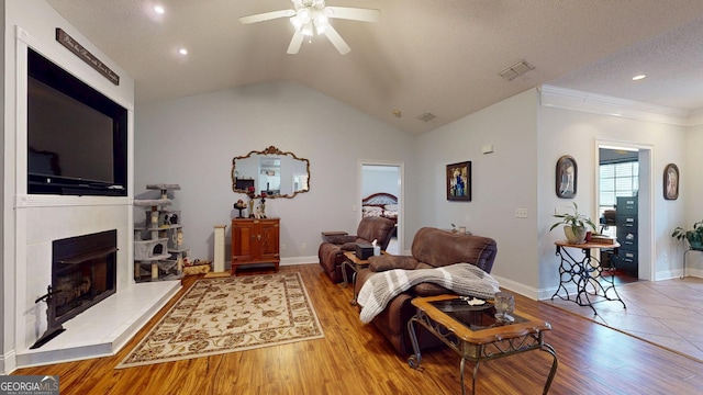 living area featuring a fireplace with raised hearth, ceiling fan, wood finished floors, and lofted ceiling