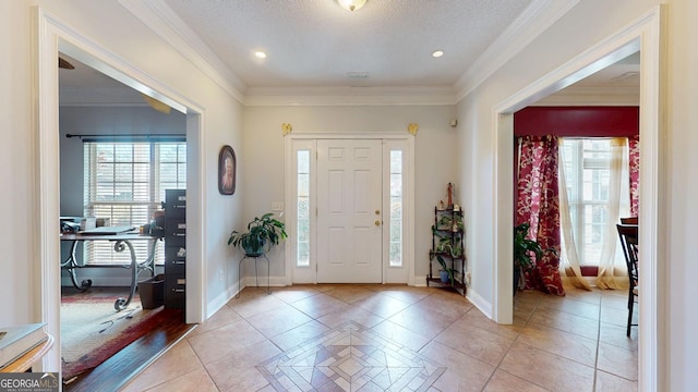 entryway featuring ornamental molding, light tile patterned flooring, a textured ceiling, and baseboards