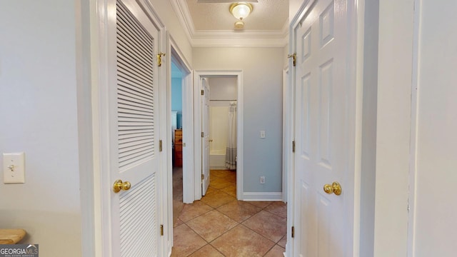 hallway featuring a textured ceiling, ornamental molding, light tile patterned flooring, and baseboards