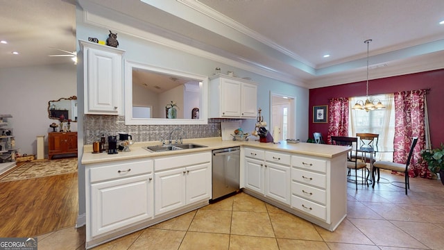 kitchen with a raised ceiling, a sink, backsplash, and stainless steel dishwasher