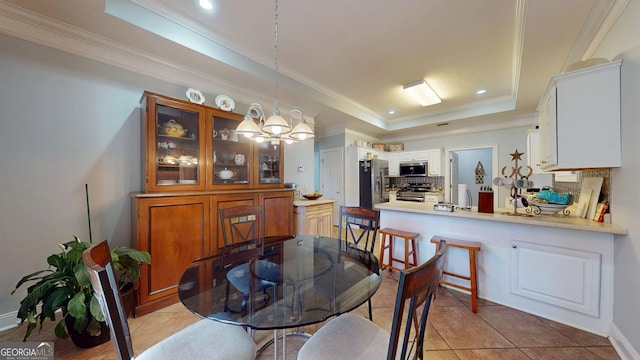 dining space featuring ornamental molding, a tray ceiling, light tile patterned flooring, and an inviting chandelier