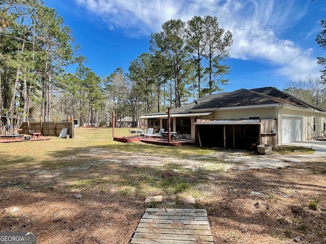 view of yard with a deck, driveway, and a garage