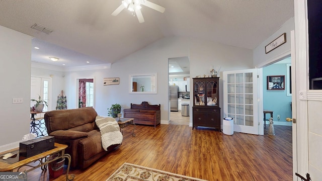 living area with ceiling fan, baseboards, vaulted ceiling, and wood finished floors