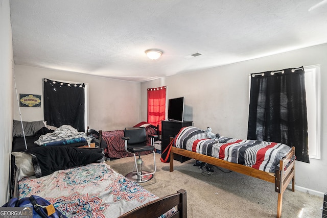 carpeted bedroom with visible vents, baseboards, and a textured ceiling