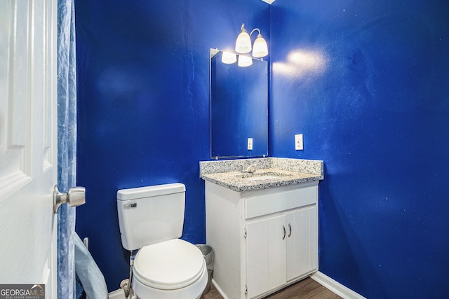 bathroom featuring vanity, toilet, wood finished floors, and baseboards