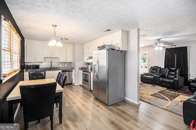 kitchen featuring visible vents, light wood-type flooring, white cabinets, appliances with stainless steel finishes, and open floor plan