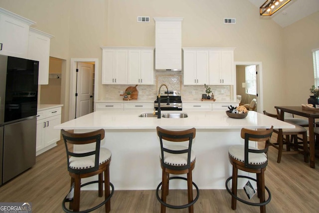 kitchen with stainless steel appliances, white cabinets, visible vents, and a sink