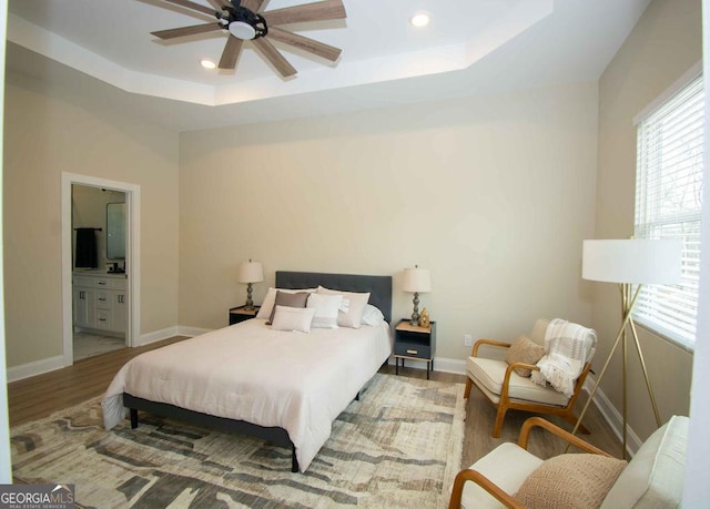 bedroom featuring light wood finished floors, baseboards, a tray ceiling, and recessed lighting