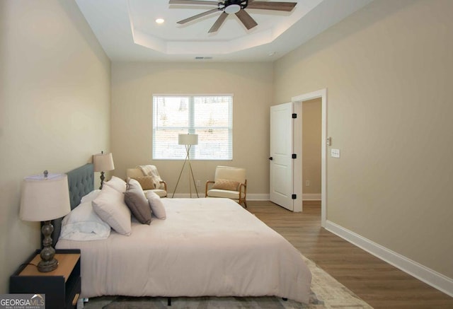 bedroom with a raised ceiling, baseboards, and wood finished floors