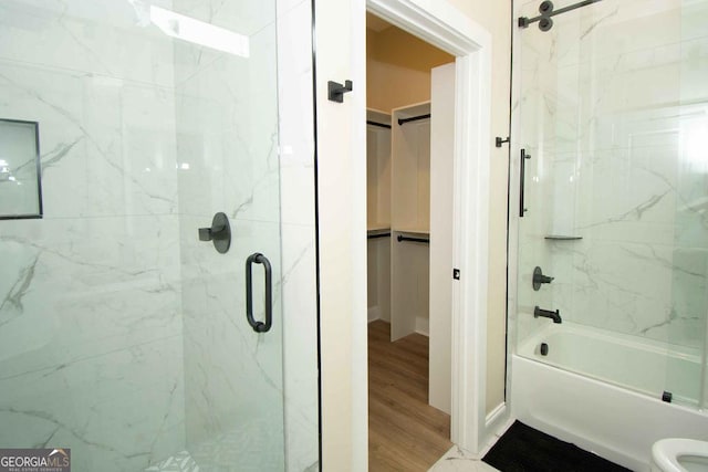 bathroom with toilet, bath / shower combo with glass door, a walk in closet, and wood finished floors