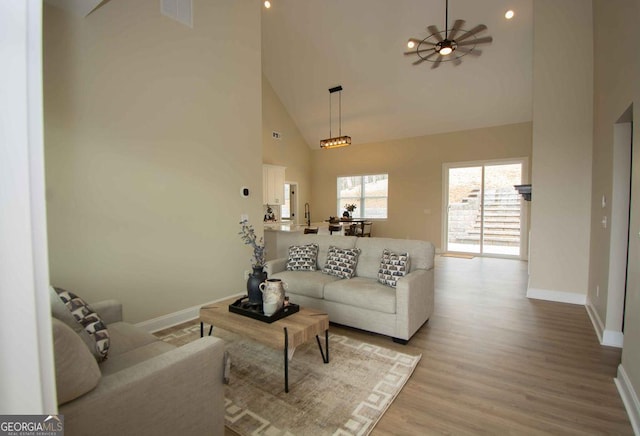 living room with baseboards, visible vents, ceiling fan, wood finished floors, and high vaulted ceiling