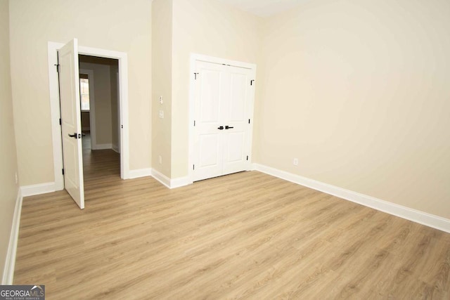 unfurnished bedroom with light wood-type flooring, a closet, and baseboards