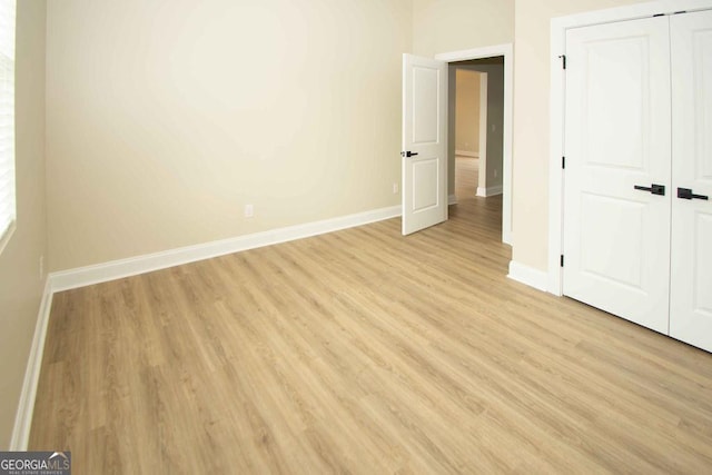 unfurnished bedroom featuring light wood-type flooring, a closet, and baseboards