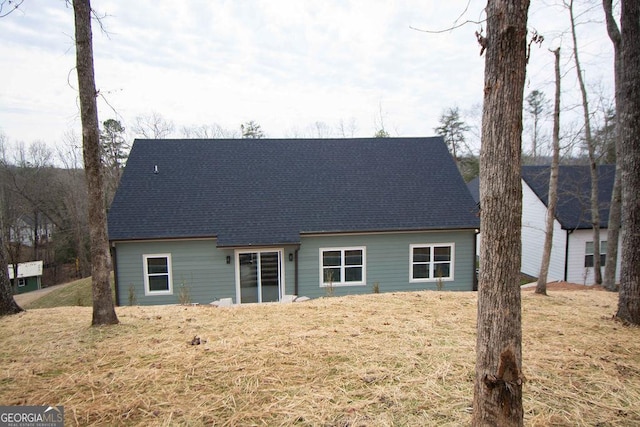 rear view of property with a yard and a shingled roof