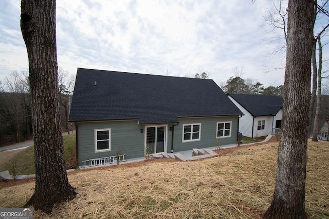 back of house with roof with shingles and a yard