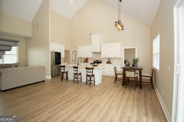 kitchen with stainless steel electric stove, a breakfast bar area, white cabinetry, and custom range hood