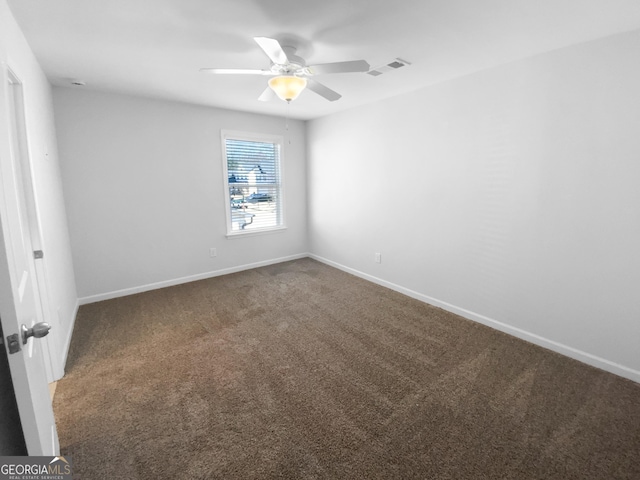 carpeted spare room with baseboards, visible vents, and ceiling fan