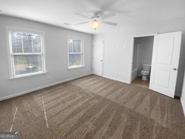 unfurnished bedroom featuring carpet floors, visible vents, a ceiling fan, connected bathroom, and baseboards