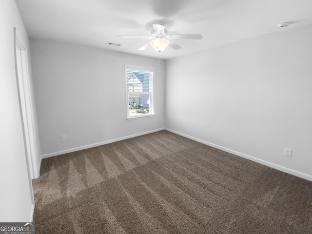 spare room with carpet floors, visible vents, baseboards, and a ceiling fan