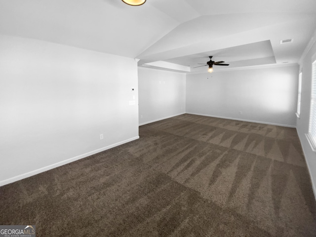 carpeted spare room featuring lofted ceiling, a raised ceiling, visible vents, and baseboards